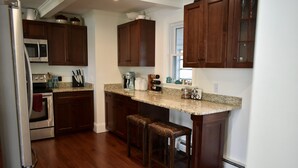 A kitchen with wooden cabinets, a granite countertop, a built-in oven, and a refrigerator. - Meredith Bay - Brand New 1st Floor Apartment In Private Home (Meredith)