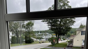 A view from a room with a large window overlooking a street with houses, a stop sign, and a fire hydrant. - Meredith Bay - Brand New 1st Floor Apartment In Private Home (Meredith)