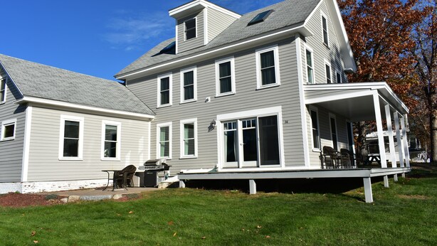 A two-story house with a covered porch and a small deck. - Meredith Bay - Brand New 1st Floor Apartment In Private Home (Meredith)