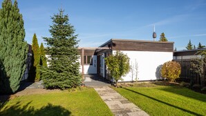 A modern house with a well-maintained lawn, a stone pathway, and tall evergreen trees.