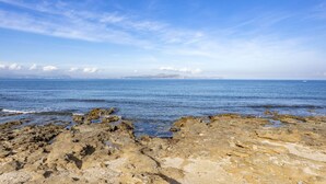 A rocky shoreline with clear blue water and distant mountains. - Villa by the sea with 4 bedrooms, 2 bathrooms, barbecue and terraces (Colonia de Sant Pere)