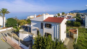 A coastal residential area with white buildings, red-tiled roofs, and a clear view of the sea. - Villa by the sea with 4 bedrooms, 2 bathrooms, barbecue and terraces (Colonia de Sant Pere)