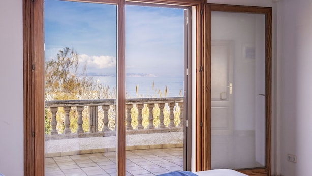 A bedroom with a large sliding glass door leading to a balcony with a view of the sea and trees. - Villa by the sea with 4 bedrooms, 2 bathrooms, barbecue and terraces (Colonia de Sant Pere)