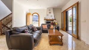 A living room with a leather sofa, wooden coffee table, and a view of the outside through a glass door. - Villa by the sea with 4 bedrooms, 2 bathrooms, barbecue and terraces (Colonia de Sant Pere)