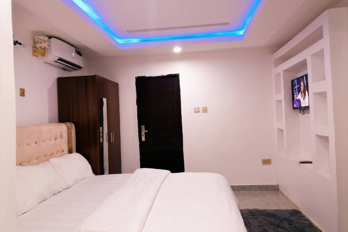 A bedroom with a bed, wardrobe, and a TV on the wall.