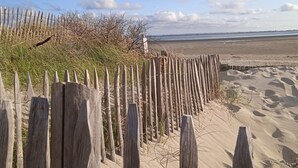Une plage de sable avec une clôture en bois et une végétation clairsemée.