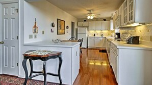 A compact kitchen with white cabinetry, a central island with stools, and a ceiling fan. - Maple Highlands: Under 1 Mile to Lift! Mountaintop Estate with 2 Scenic Decks (McGaheysville)