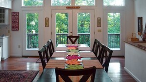 A dining room with a long table, chairs, and a view of a balcony with greenery. - Maple Highlands: Under 1 Mile to Lift! Mountaintop Estate with 2 Scenic Decks (McGaheysville)