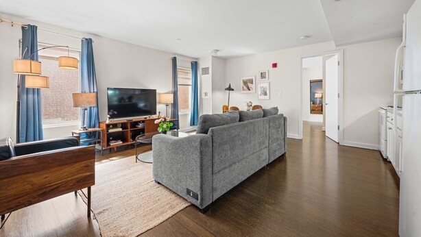 Ein modernes Wohnzimmer mit grauem Sofa, einer Holz-Unterhaltungsecke und einem Flachbildfernseher.