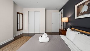 Ein Hotelzimmer mit einem Bett, einem Nachttisch, einer Lampe, einem gerahmten Bild und einer Tür.