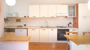 A compact kitchen with white cabinets, a microwave, a sink, a stove, and a dishwasher. - Bright Finalborgo Apartment - BBQ, Bike Storage, Garden (Finale Ligure)