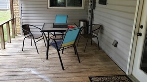 Une terrasse couverte avec une table et des chaises, une fenêtre et une porte.