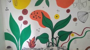 Un dormitorio con cama, un mural en la pared y una mesita de noche.