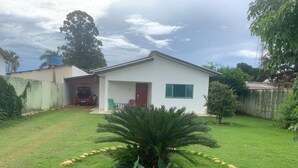 Una casa de un piso con garaje, rodeada de un césped cuidado y un jardín circular con plantas.