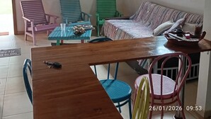 Un espacio acogedor con una mesa de madera, sillas coloridas, un sofá y una estantería.