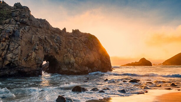 A rocky coastline with a cave-like formation and waves crashing onto the shore. - Ocean & Mountain View Home - Walk to Trails, Beach, Family Activities (Montara)