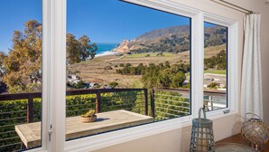 A balcony with a view of the ocean and hills, a wooden table, and a lantern. - Ocean & Mountain View Home - Walk to Trails, Beach, Family Activities (Montara)