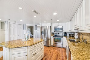 A kitchen with white cabinets, granite countertops, stainless steel appliances, and wooden flooring.