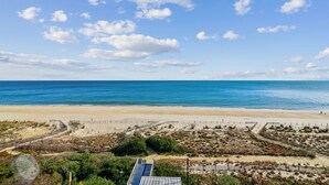A beach view with a clear sky, sandy beach, and a fenced area with vegetation. - DAILY ACTIVITIES & LINENS INCLUDED*! Lovely direct Oceanfront, 2 bedroom (Den converted to a third bedroom, there is a pocket door for privacy with a queen bed, closed from kitchen but open to entry) 2 bath condo. (Ocean City)