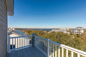 A wooden deck with a white railing overlooking a body of water and residential buildings. - Dawn By The Bay-Designer Decor with Great Ocean Views, Sleeps 12 (Surf City)
