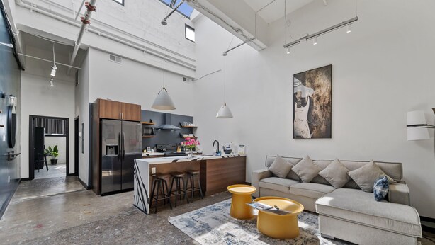 A modern kitchen with a central island, bar stools, and a dining area with a sofa and coffee table. - Industrial Loft 5 min to Children’s Hospital, slps 4 (Pittsburgh)