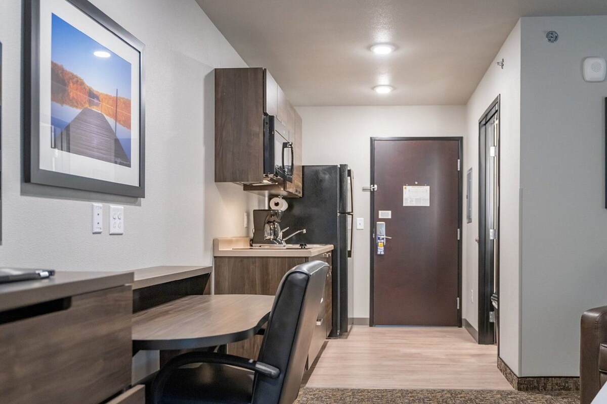 A compact kitchen with a dining area, a refrigerator, and a door with a notice.