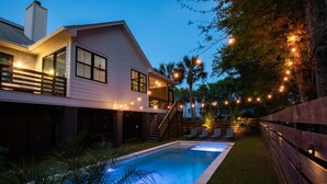 A two-story house with a swimming pool, wooden deck, and string lights. - Pool, Hot Tub & Perfect Fall Beach Days (Isle of Palms)