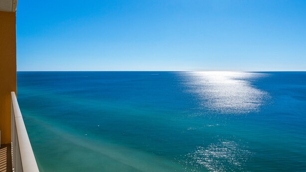 A clear view of the ocean from a balcony with a railing.