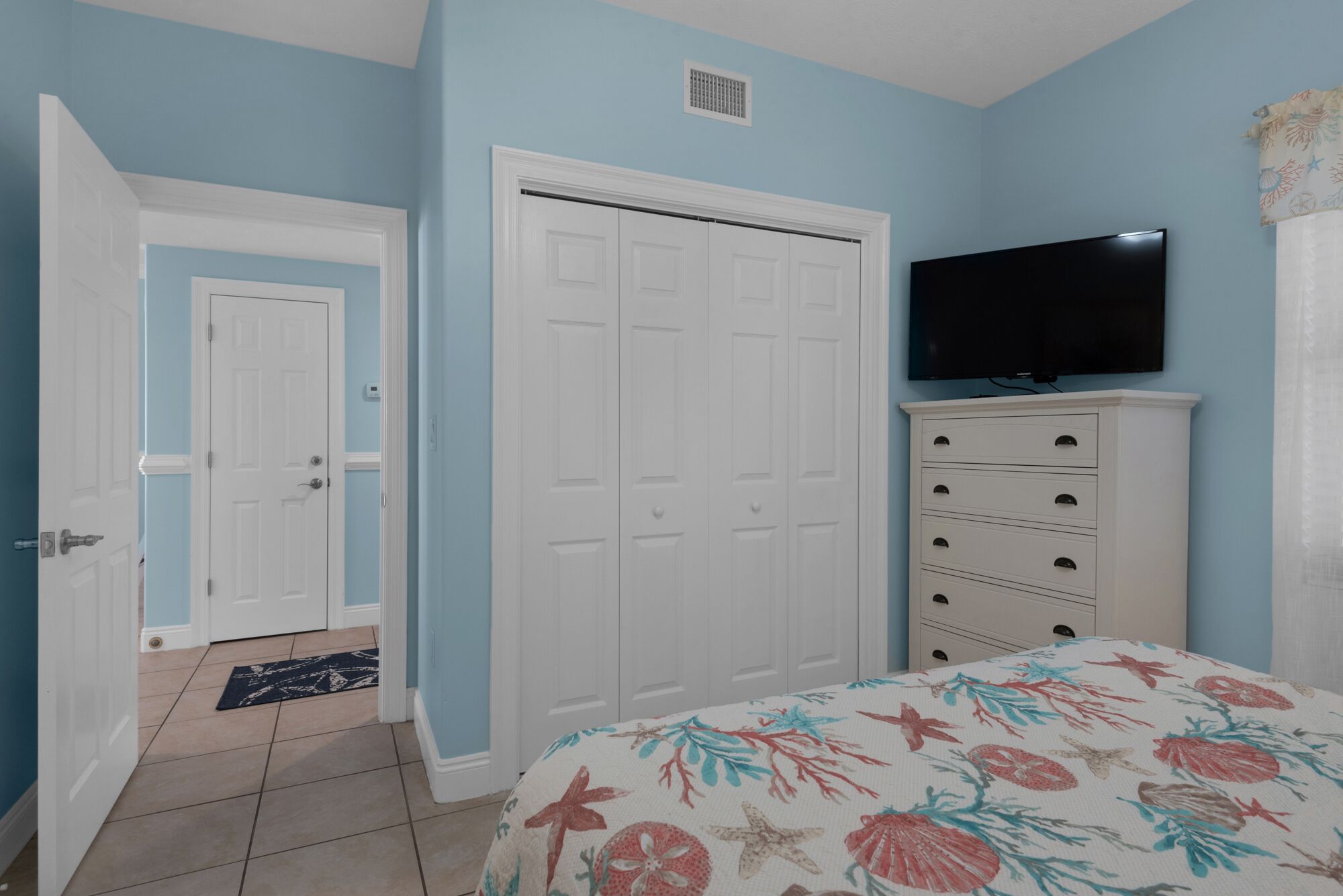 A bedroom with a bed, a wardrobe, a television, and a door.