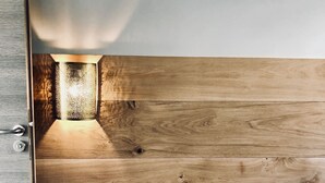 A bedroom with a wooden headboard, a bedside table, and a wall-mounted light fixture. - TROUVILLE 3 Bdrms 65m2 SPLENDID AND CLEAR VIEW, BATHED IN LIGHT (Trouville-sur-Mer)