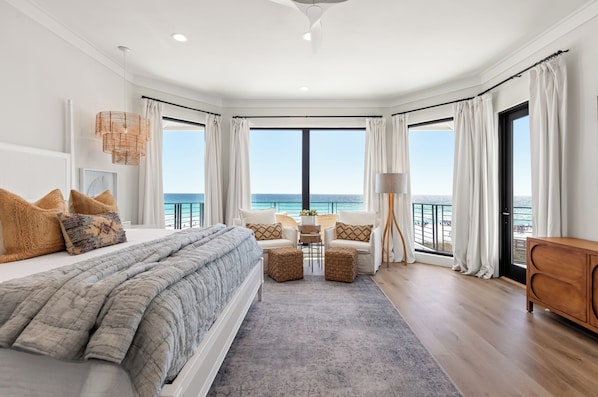 Un dormitorio con una cama grande, vistas al mar, un balcón y un armario de madera.