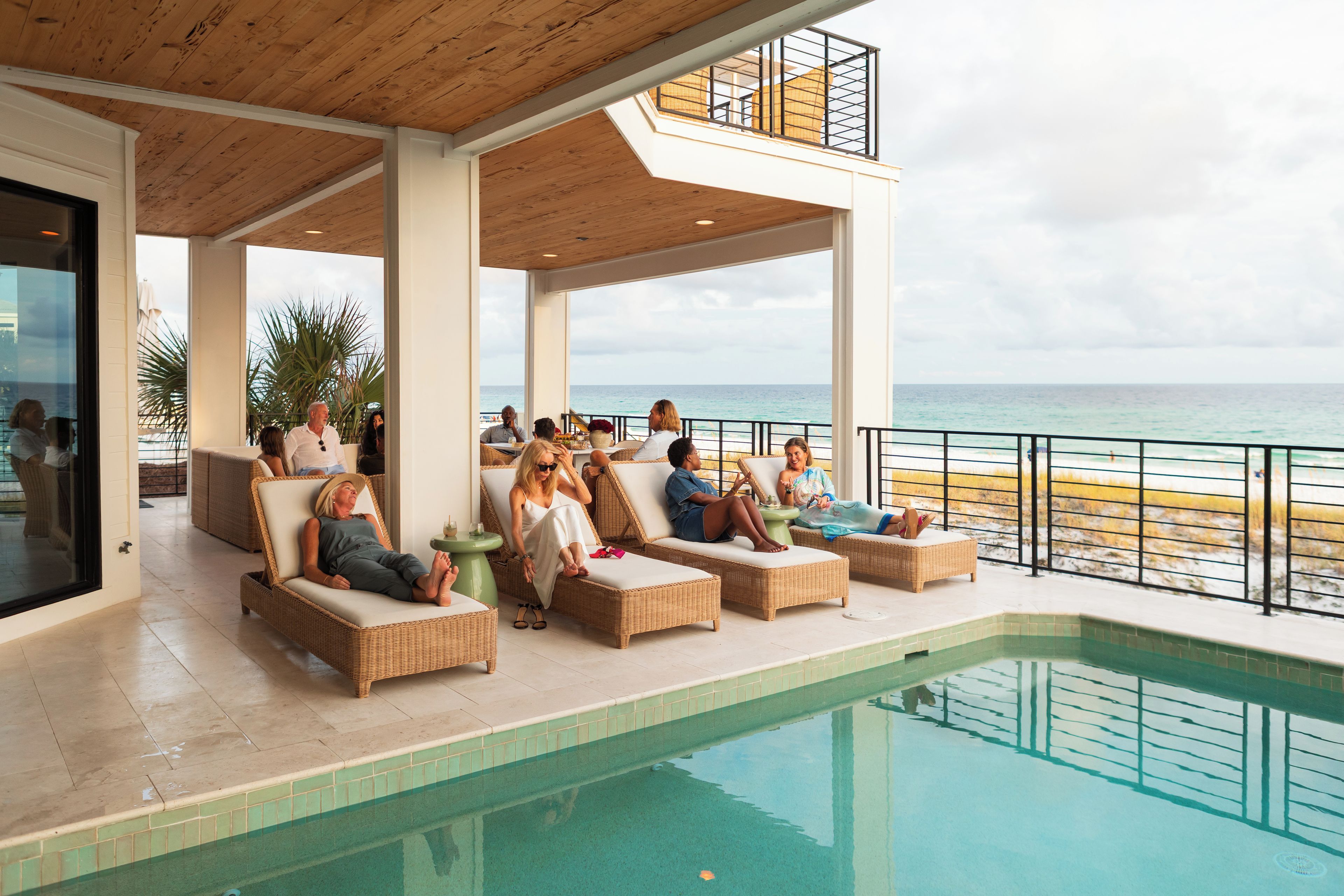 Ein Poolbereich mit Korlounge-Stühlen und Blick auf das Meer.