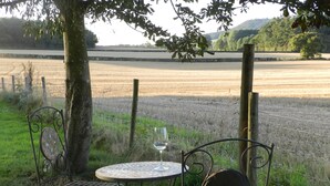 Mesa e duas cadeiras sob uma árvore, com um copo de vinho sobre a mesa.