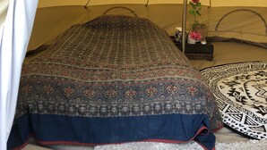 Uma tenda com um cobreleite estampado, uma planta decorativa e um tapete.