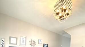 Ein modernes Wohnzimmer mit Holzboden, einer schwarzen Bank, einem weißen Konsolentisch und einem Kronleuchter.