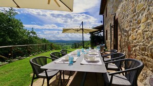 An outdoor dining area with a table set for four, surrounded by wicker chairs, under a large umbrella. - Serena al Casalone, Design apartment in Private Chianti Estate, pool WIFI A/C (San Gusme)