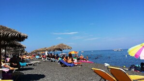 A beach with thatched umbrellas and lounge chairs. - Rodothea on the Beach. (Monolithos)