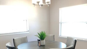 A dining area with a round table, six upholstered chairs, a potted plant, and a chandelier. - Fully Renovated Home in Downtown Clermont (Clermont)