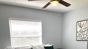A bedroom with a bed, a ceiling fan, a window with blinds, and a wall-mounted artwork. - Fully Renovated Home in Downtown Clermont (Clermont)