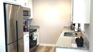 A modern kitchen with stainless steel appliances, a granite countertop, and a wooden floor. - Fully Renovated Home in Downtown Clermont (Clermont)