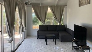 A modern living room with a ceiling fan, a gray sofa, a coffee table, and a TV stand. - Amazing View, 3 Bed Renovated, AC, Generator (St Thomas)