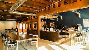 A spacious meeting house with a long table and chairs, a kitchen area, and a bar with stools. - Pet-friendly, Cozy Tiny Home with Self Check-In and Wifi! (Spokane)