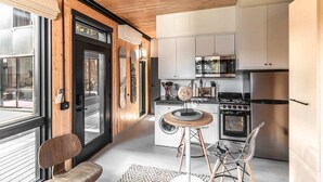 A modern kitchen with white cabinets, stainless steel appliances, and a wooden ceiling. - Pet-friendly, Cozy Tiny Home with Self Check-In and Wifi! (Spokane)