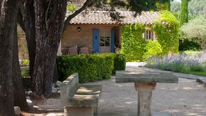 A stone bench and table in a garden with a stone building in the background.