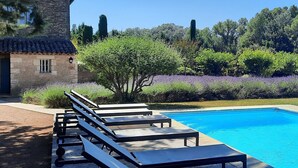 A pool with lounge chairs and a stone building in the background.