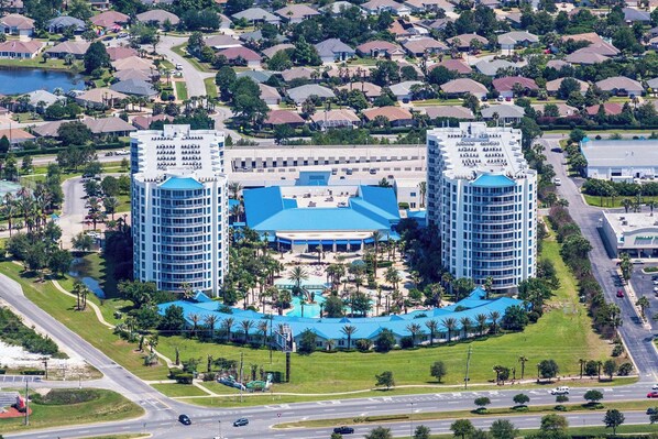 A large hotel with two prominent towers, a central building, and a swimming pool area.