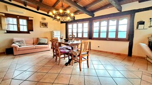 A dining area with a wooden table and chairs, a chandelier, and a view through large windows. - Mild hills Villa, on the Tuscany coast with brand new panoramic private pool (Camaiore)