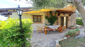 A stone patio with a table and chairs, a yellow awning, and a stone wall with greenery. - Mild hills Villa, on the Tuscany coast with brand new panoramic private pool (Camaiore)