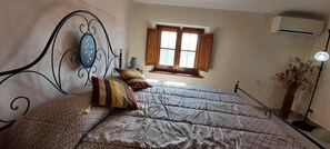 A bedroom with a bed, a window with open shutters, an air conditioner, and a lamp. - Mild hills Villa, on the Tuscany coast with brand new panoramic private pool (Camaiore)