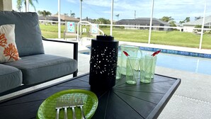 En uteplats med en inglasad del, en grön tallrik med bestick, en svart vattenflaska och glas med sugrör.